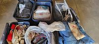 Five blue Rubbermaid boxes filled with various fabric items, bedding, and sewing supplies including yarn and scissors.