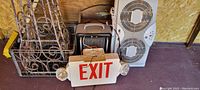 Photo showing metal racks, exit sign with emergency lights, and white window fan.