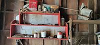 Wooden shelf with various cans and containers including gasoline and lubricant products