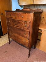 Front and angled view of antique highboy chest showing five drawers, wood grain, and brass ring pulls.