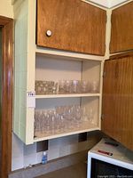 Shelves of glass drinkware including tumblers, wine glasses, and smaller glasses