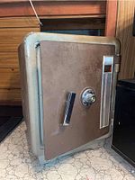 Fire resistant safe door front showing combination dial lock, handle, and surface wear.