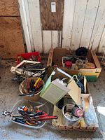 Wide view of several boxes and containers filled with assorted hand tools and hardware items, including tools, cords, and boxes of miscellaneous small hardware