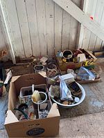 Photo showing multiple boxes containing assorted hardware items placed on floor against a wall with wooden paneling