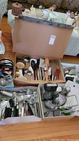 Large open box with various kitchen utensils including whisks, spoons, ladles, graters, and other gadgets.