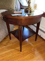 Close-up of one wood end table showing tapered leg, central drawer, and lower shelf.