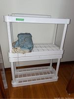 Photo of white resin shelving unit with three shelves and scrap fabric folded inside