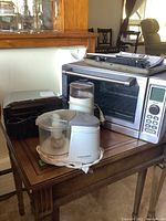 Photo showing Cuisinart toaster oven, Black & Decker chopper, Braun coffee grinder, and Black & Decker hand mixer placed on wooden table.