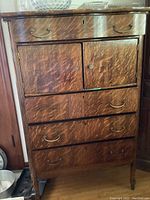 Full frontal view of tiger oak cabinet showing four drawers, two doors with lock, and mismatched brass hardware.