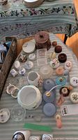Top view showing porcelain, glass, and wooden trinket boxes along with napkin rings on a striped floral tablecloth.