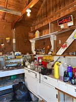 Wide view of workbench, shelves, and wall space showing various tools, jars, bins, and containers in a wooden garage setting.