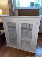 Front view of white painted wood display cabinet with two glass doors showing the three internal shelves.