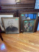 Four framed vintage prints and photographs grouped on wooden floor, showing variety of frame styles and image subjects.