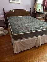 Full view of the wood double bed with Sealy mattress on top, showing headboard and turned posts in a bedroom setting.