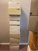 Stacked white storage boxes labeled by year (1980-1989) against wall