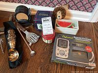Overview of assorted barware including ice cream scoop, coasters, cooking thermometer in box, and boxed candies with price tag