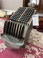 Side and front angled view of the Brandt coin counter showing its buttons, coin slots and metal body with intricate designs.