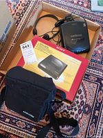 Sony Car Discman with original box, headphones, and black carrying case placed on a patterned rug.