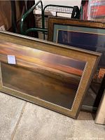 Three photographs stacked, two large framed landscape photographs visible with sunset or sunrise scenes in warm tones.