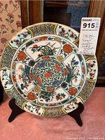 Front view of Limoges oriental pattern charger on wooden stand with visible detailed floral design.