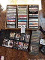 Multiple rows of cassette tapes in three wooden trays plus additional loose tapes laid out below. Visible titles include 'The Eagles', 'Steel Guitar Rag' and 'Totally Country'.