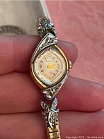 Close-up of one women's wrist watch showing the gold-tone dial with Arabic numerals and intricate bezel design