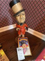 Full view of carved WC Fields figure with orange coat and beige top hat, alongside VHS tape featuring WC Fields illustration.