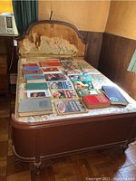 Full view of the vintage wooden bed frame with damaged, torn upholstered headboard and mattress with books on it showing scale and condition.