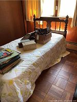 Full bed frame setup on a twin mattress showing wooden spindled headboard, with boxes and papers on mattress covering mattress and contents not included.