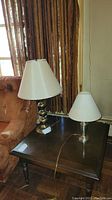 Two table lamps on a wooden end table next to a couch, showing relative sizes and shades.