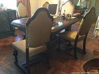 Dining table with one captains chair and five matching chairs arranged around it, showing overall size and upholstery.