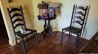 Photo showing the two vintage ladder back chairs and small round table with items on top.
