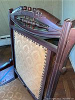 Back view of the chair showing the carved wooden top rail and upholstered backrest with nailhead trim.