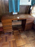 Front view of vintage wooden desk showing six drawers and worn top surface with scratches.