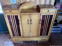 Front view of full wooden Deco cabinet showing two top drawers, red panel side doors, and central doors with vertical detailing.