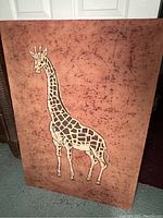 Photo showing front view of rectangular giraffe tapestry with warm rust background and black patterns, giraffe centered.