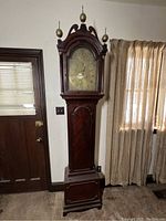 Full frontal view of complete grandfather clock in room setting
