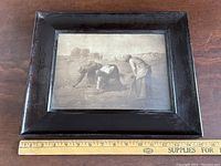 Full view of the framed print showing three women gleaning grain in a field, in a dark oak frame.