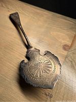 Full view of the engraved silver cake server showing intricate designs on the blade and tapering handle.