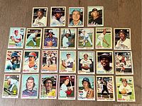 Top-down photo showing 28 miscellaneous 1978 OPC baseball cards in a grid pattern on a wooden surface. Players include a mix of pitchers, catchers, and fielders from various MLB teams.