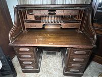 Full view of vintage wooden roll top desk showing cubbies and drawers with partial roll top closure.