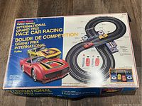 Closed box of Radio Shack International Grand Prix slot car racing set showing front art with cars and track layout.