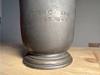 Close-up of engraved text 'Peter Calamai June 23 1943' on mug body