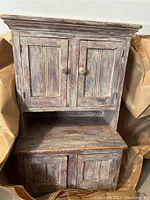 Front view of the closed wooden doll-sized hutch showing double doors in upper and lower sections, with wood knobs.