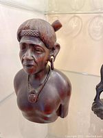 Front view of the carved wooden female bust figurine with detailed hairstyle, earrings, and necklace.