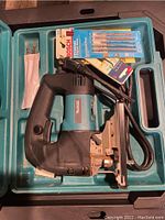 Overview of Makita jig saw in blue carrying case along with Bosch jigsaw blades and accessories.