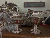 Close-up image showing silverplate cream and sugar server with ornate handles and decorative beaded rims.