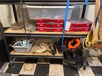 Photo showing bottom two shelves with tool belt, bins and organizers of fasteners and tools.