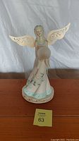 Front view of the solar angel figurine with the globe and removable wings on a wood surface.