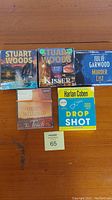 Five compact disc audio book cases arranged on wood surface. Titles visible: Strategic Moves and Kisser by Stuart Woods; Murder List by Julie Garwood; The Touch by Coleen McCullough; Drop Shot by Harlan Coben.